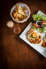 Grilled chicken steak with lettuce salad cherry tomatoes mushrooms herbs  on  white plate and wooden background. Traditional cuisine. Grill kitchen.