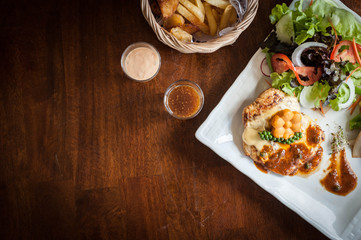 Grilled chicken steak with lettuce salad cherry tomatoes mushrooms herbs  on  white plate and wooden background. Traditional cuisine. Grill kitchen.