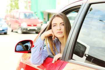 Beautiful young girl sitting in red car