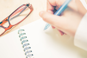 Business women hands working writing notebook on wooden desk, lighing effect