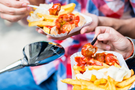 Mann und Frau essen Deutsche Spezialit&auml;t Currywurst Pommes auf dem Motorroller
