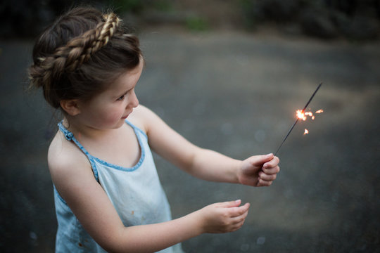 Young girl with braided hair, holding sparkler