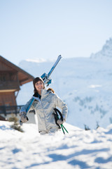 femme souriante qui porte des skis sur l'épaule
