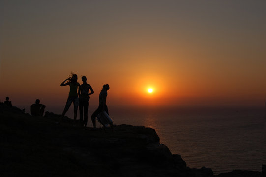 Silhouettes on mountainside on of sunset and sea
