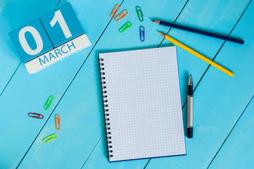March 1st. Day 1 of month, calendar on blue wooden table background. Spring time, empty space for...