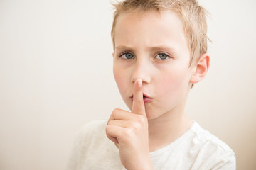 Boy with finger on lips making a silent gesture