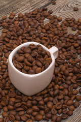 small white cup with coffee beans on wooden background