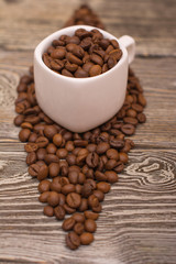 small white cup with coffee beans on wooden background