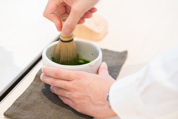 Fototapeta na wymiar Tea master make matcha tea with tea whisk 
