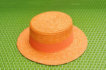 Fototapeta na wymiar Orange hat on green weave sofa.