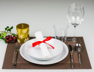 Christmas table setting with golden candle and butcher's broom