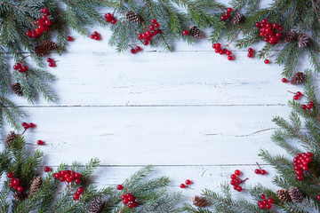 Christmas wooden background with branches of trees, pine cones and red berries