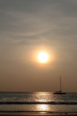 Fototapeta na wymiar silhouette of a sailingboat at sunset on the seashore