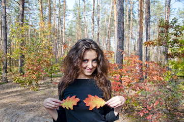 pretty woman with oak leaves in forest