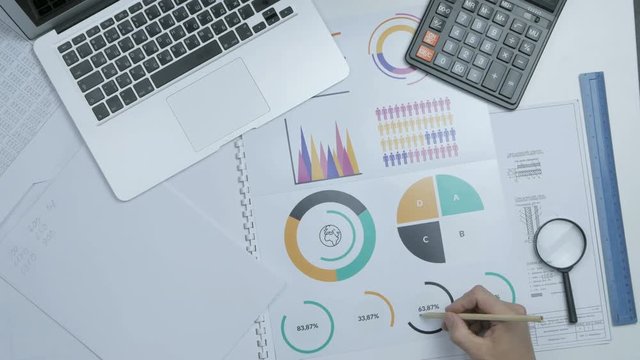 Modern office business background. Businessman with laptop computer, charts and graphs from above. 4K.