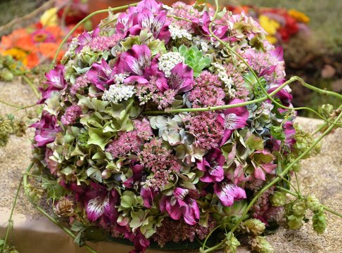 Dekoratives Kugelgebinde aus Herbstblumen - lila Inkalilien mit Fette Henne und Zweigen