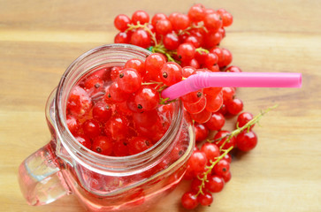 Redcurrant juice and Straw on wooden background.