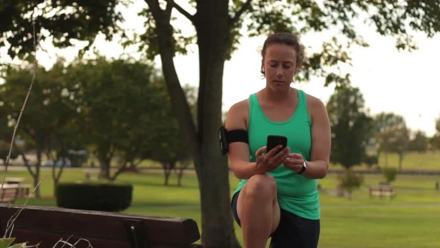 Woman Checking Smartphone Stats While Exercising in Park