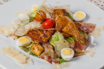 fried poultry meat with boiled eggs and herbs on a white plate