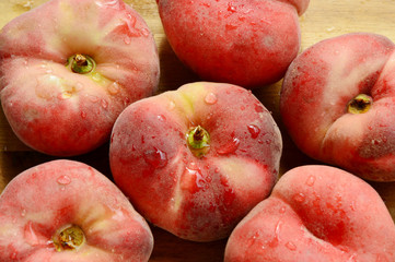 Dough nut peaches also known as Saturn peach with water drop on wooden board.
Benefits of Dough nut peaches. 
