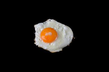 Fried egg on a black background, delicious breakfast.