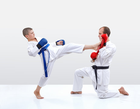Kicking karateka hits the fitness machine that keeps coach