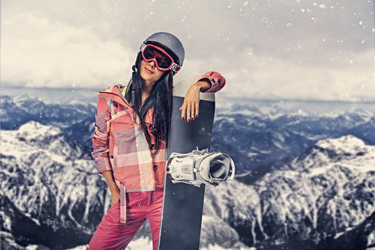 Sporty female holds snowboard in mountains.