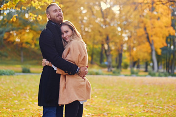 Redhead male hugs cute blonde female in autumn wild nature backg