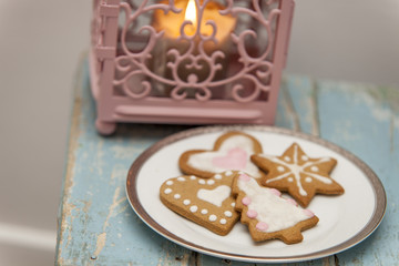 Ginger bread winter cookies with handmade icing on a blue table with pink candle latern