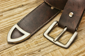 leather belt with a buckle on a wooden board