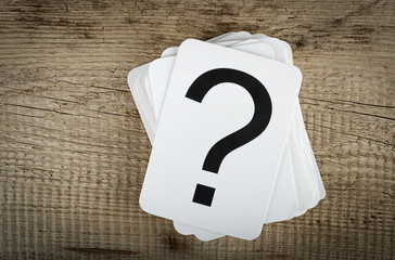 Stack of cards with a question mark on wooden background