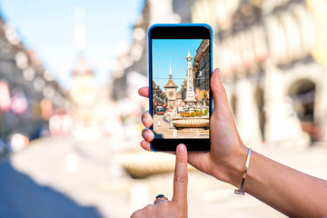 Photographing with smart phone a street view in the center of the old town of Bern city in...