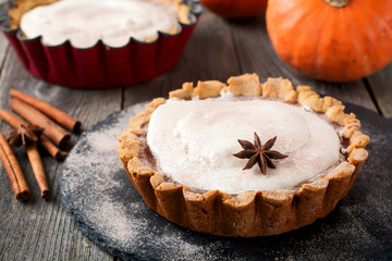 Pumpkin pie with meringue and cinnamon on old wooden background. Selective focus.