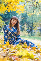 beautiful, dreamy girl with long straight hair in a blue long dress in the park in autumn