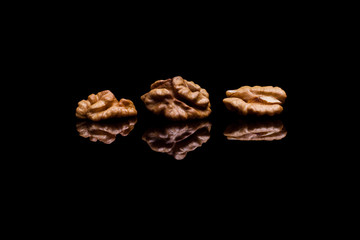 Three walnuts isolated on black reflective background