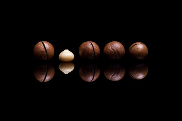 Five macadamia nuts isolated on black reflective background