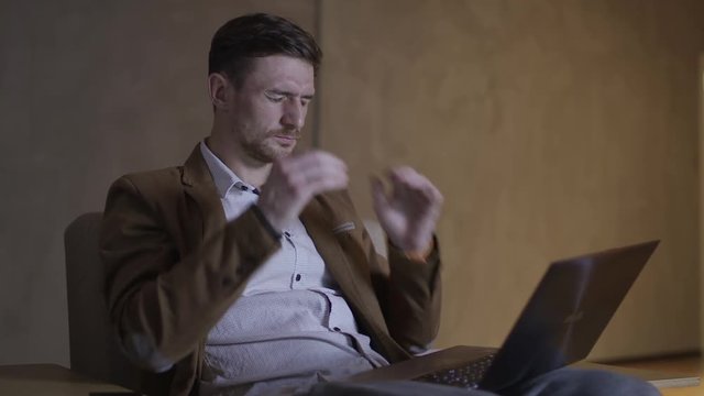 Businessman with a headache is sitting in an armchair.