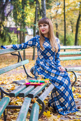 beautiful, dreamy girl with long straight hair in a blue long dress in the park in autumn