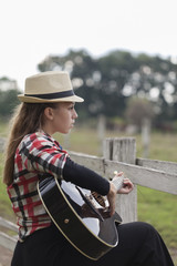 A young girl with a guitar in the nature