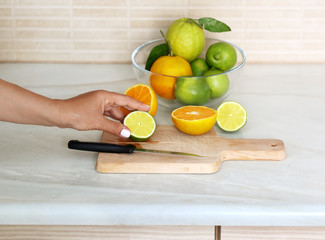 Girl's hand with a knife cutting lemon on wooden board