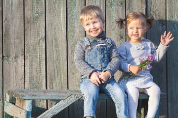 Happy children outdoor at fall season, sitting at bench. First date