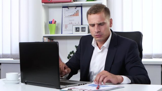 Man intently typing on a computer and writes information