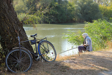Obraz na płótnie Canvas Woman fishing. Sunny day near the river.