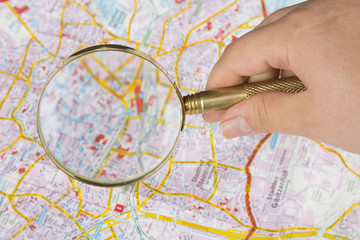 Tourism concept. Womans hand holding magnifying glass above city map