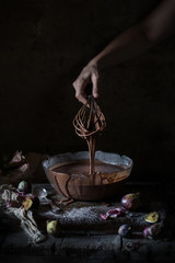 Chocolate Cake Batter Pouring, Dripping from Whisk on Dark Background
