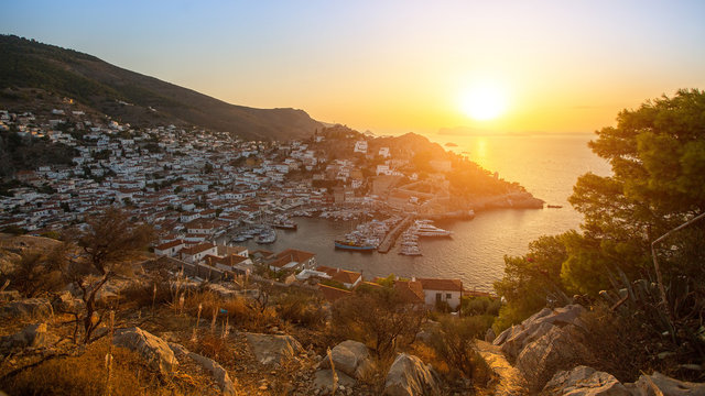 Beautiful sunset of Hydra island, Greece - top view of city center and yaht marina.