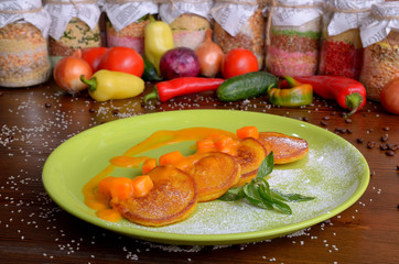 pancakes in a round green plate with chunks of pumpkin and pumpkin sauce, mint leaves and sugar