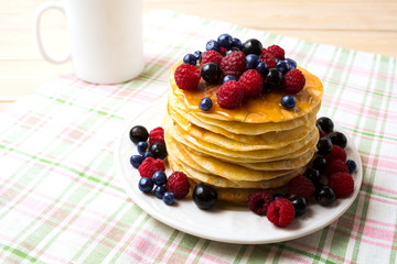 Breakfast pancakes with honey and fresh berries and coffee mug