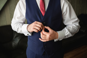 Fototapeta na wymiar Man preparation. Handsome man fastens a button of blue jacket. Wedding groom preparation. Men accessories