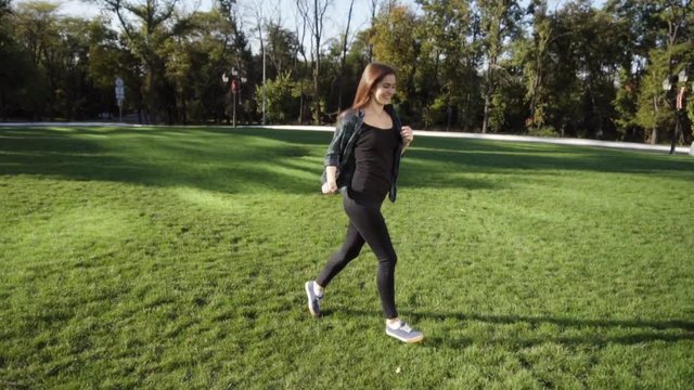 Cute young woman running at the grass in park, slow mo